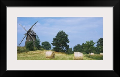 Hay bale in a field with a traditional windmill in the background, Riddarfjarden, Narke, Sweden