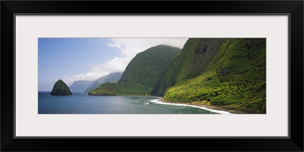 Wide angle photograph taken of immense cliffs that line the coast of a Hawaiian island.