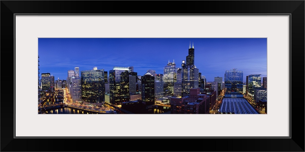 Panoramic photograph at nighttime displays the bright buildings and high-rises that hover over the busy streets of this la...