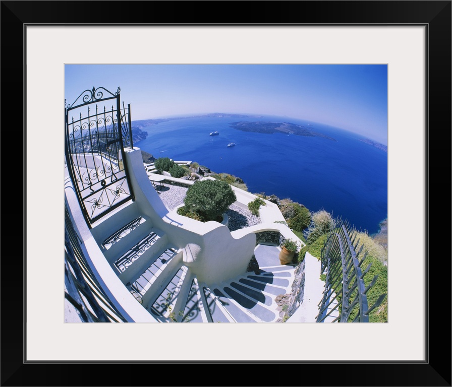 Wall docor of white curving steps leading to a courtyard overlooking the Mediterranean Ocean.
