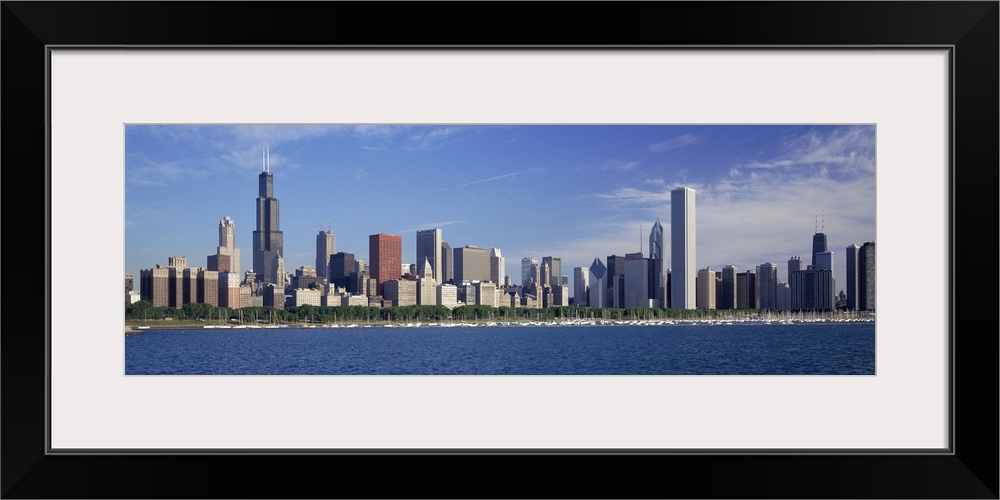 Panoramic photograph of skyline and waterfront under a cloudy sky.