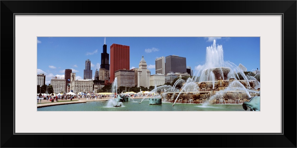 Panoramic view of the Buckingham Fountain in the center of the busy city on a warm, sunny day.