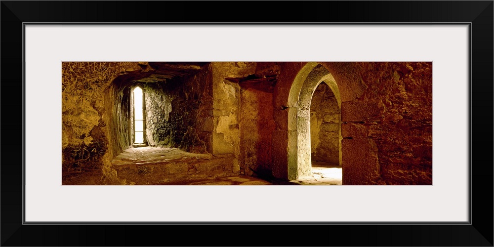 Panoramic photograph of the inside of an old stone palace with arched doorways.