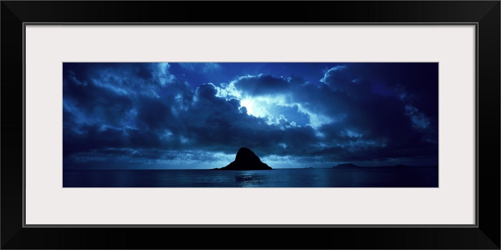 Panoramic photo at dusk of the Chinaman's Hat (Mokolii) island alone in the middle of the ocean in Oahu, Hawaii (HI). The ...