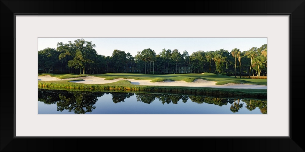 Reflection of an urban forest in still waters at the edge of a sand trap in a Southern US town.