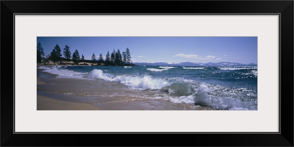 Panoramic photograph shows the waves of a large body of water in Nevada crashing against a sandy shoreline scattered with ...