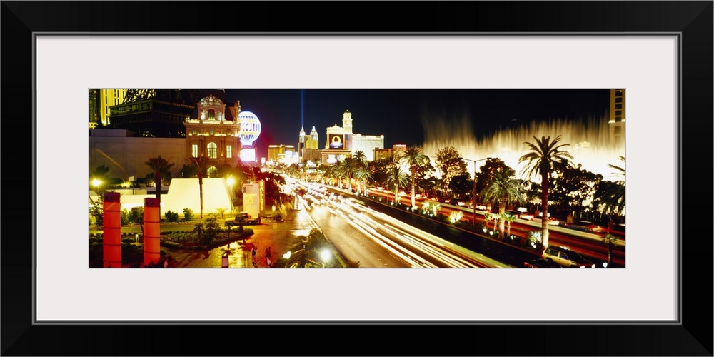 Panoramic photograph of light trails from cars driving down the Las Vegas strip, bright lights shining around Paris and th...