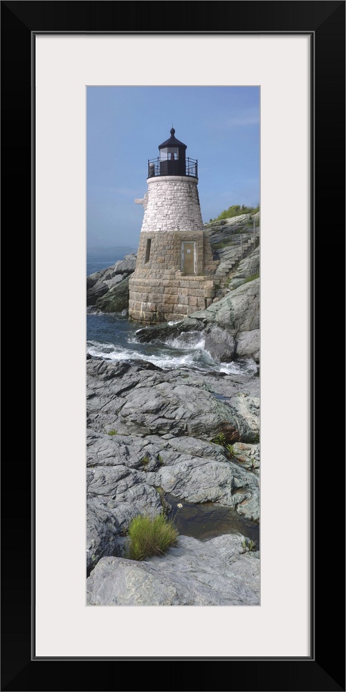 This is a vertical photograph of light house on a rocky coast.