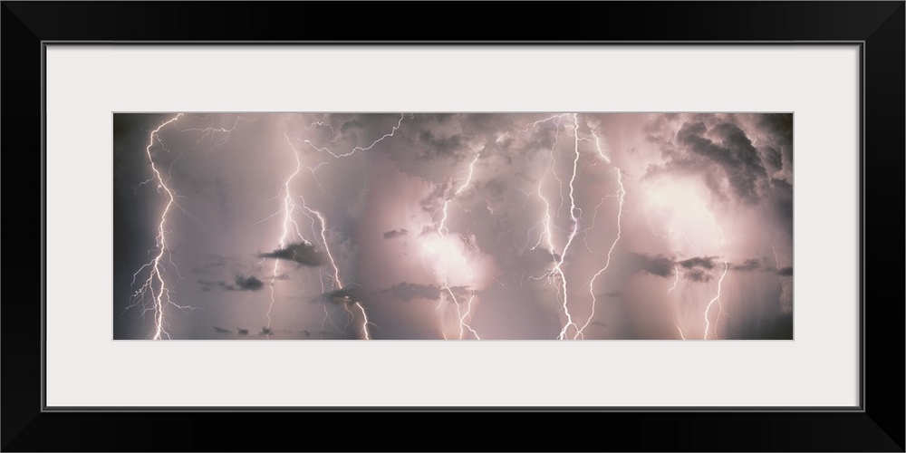 Panoramic canvas of lightning strikes up close against a stormy lit up sky.