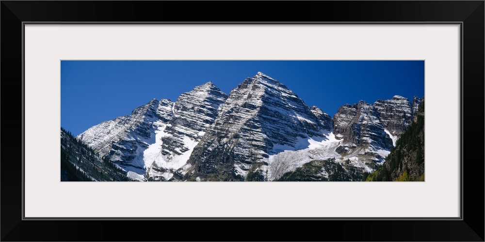 Panoramic photo on canvas of rugged mountains with snow on them.