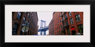 Low angle view of a suspension bridge viewed through buildings, Manhattan Bridge, Brooklyn, New York City, New York State