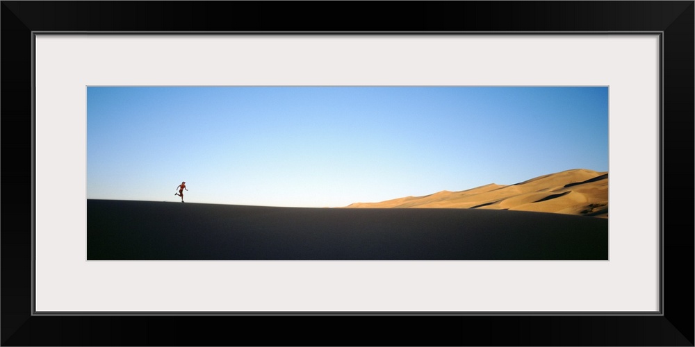 Low angle view of a woman running in the desert, Great Sand Dunes National Monument, Colorado