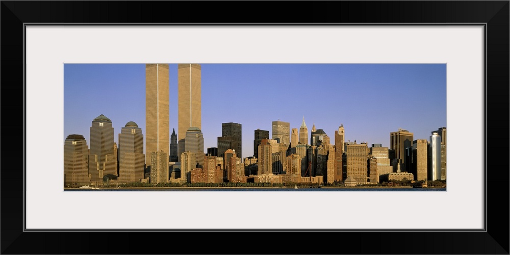 The Manhattan skyline is pictured in an elongated view at the end of the day when the sun is beginning to set.