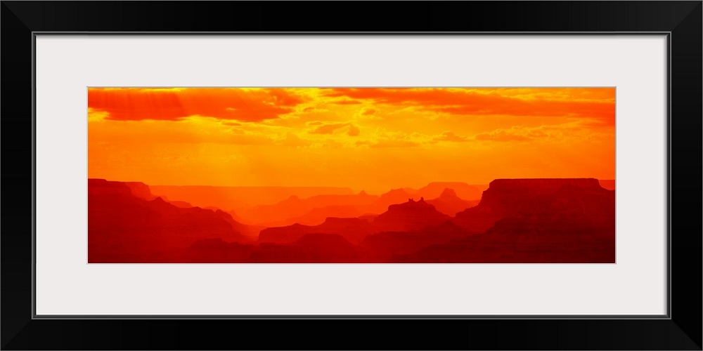 Tonal panoramic photograph of canyon silhouettes at sunrise.