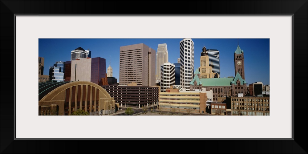 Big, panoramic photograph of the Minneapolis skyline against a blue, afternoon sky.