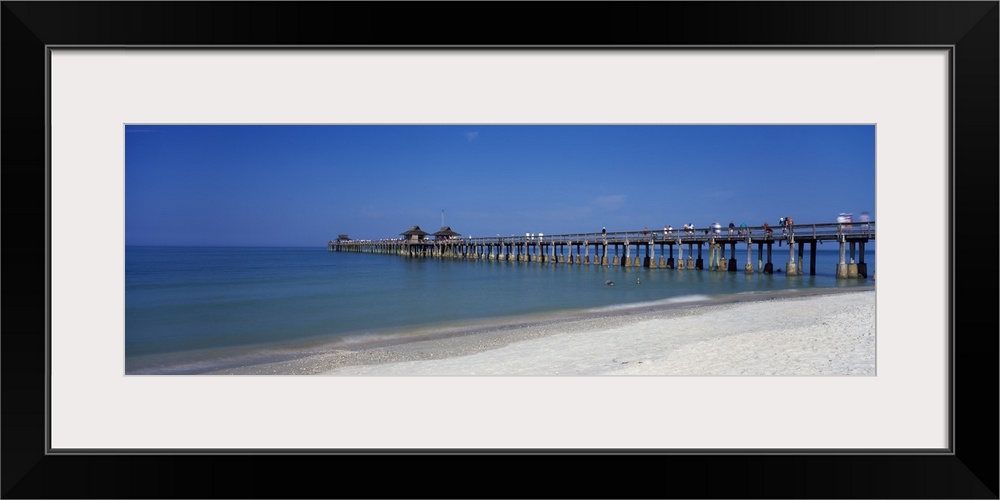 This wall art is a panoramic photograph of a beach board walk extending into the ocean.