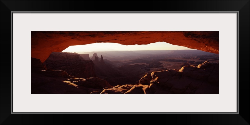 View through a stone arch in the morning, looking over the desert valley of eroded rock.