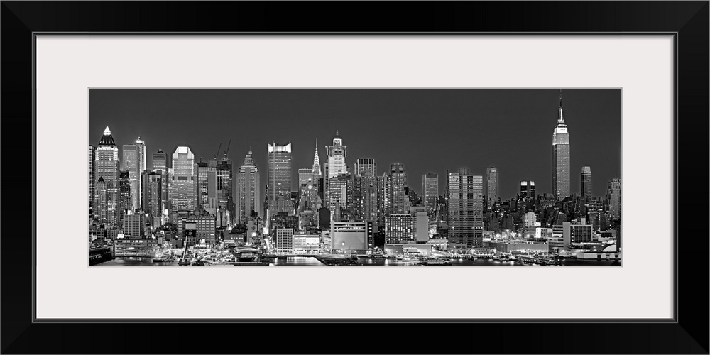 The dense Manhattan skyline, as view from west of the city, is outlined and illuminated by lights in the night.