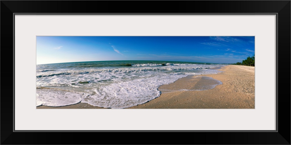 Panoramic photograph displays waves from the Gulf of Mexico as they gently break onto a sandy beach within Florida.
