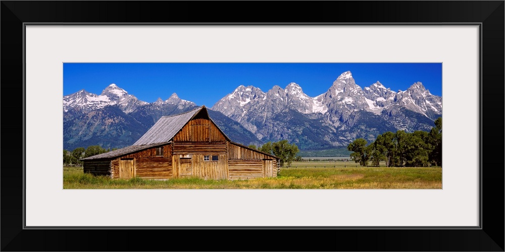 A panoramic landscape photograph of farmland, the T.A. Moulton barn, and the massive mountain peaks in the background.