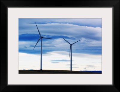 Pair of wind farm turbines, cloudy sky, Montana