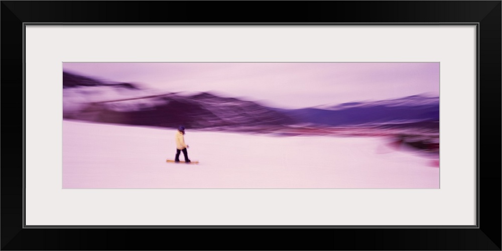 Panoramic photo of someone snowboarding down a mountain printed on canvas.