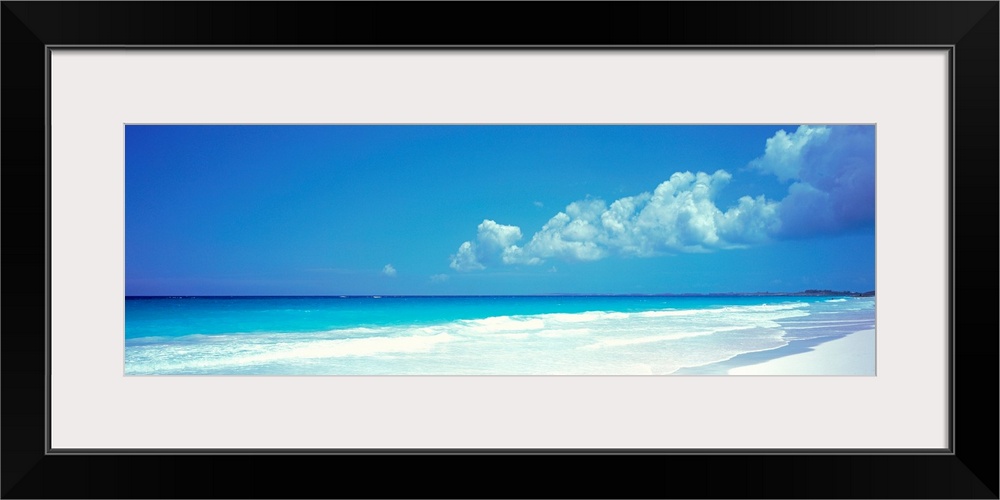 Panoramic photograph includes a near cloudless sky overlooking a sandy beach as the waves from the Atlantic Ocean gently c...