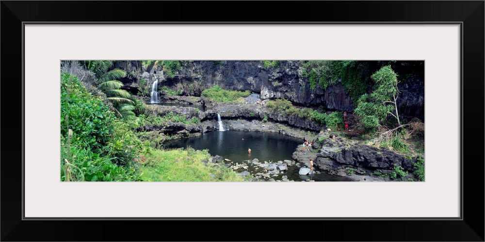 This large panoramic piece is a photograph taken of small waterfalls that go into a pool of water in the middle of a fores...