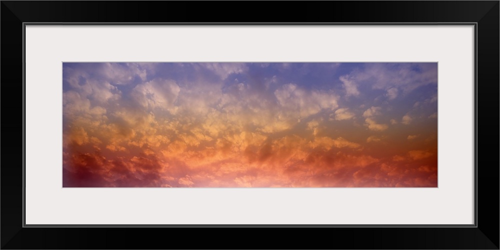 Panoramic photograph of colorful clouds illuminated by the sun.