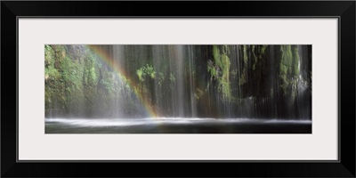 Rainbow formed in front of waterfall in a forest, California,