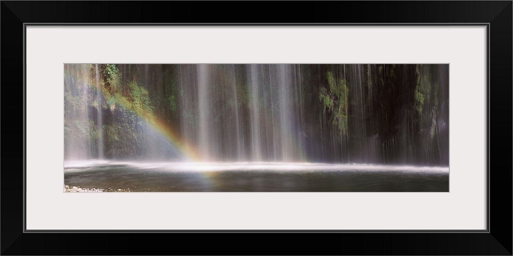 Rainbow formed in front of waterfall in a forest, California,