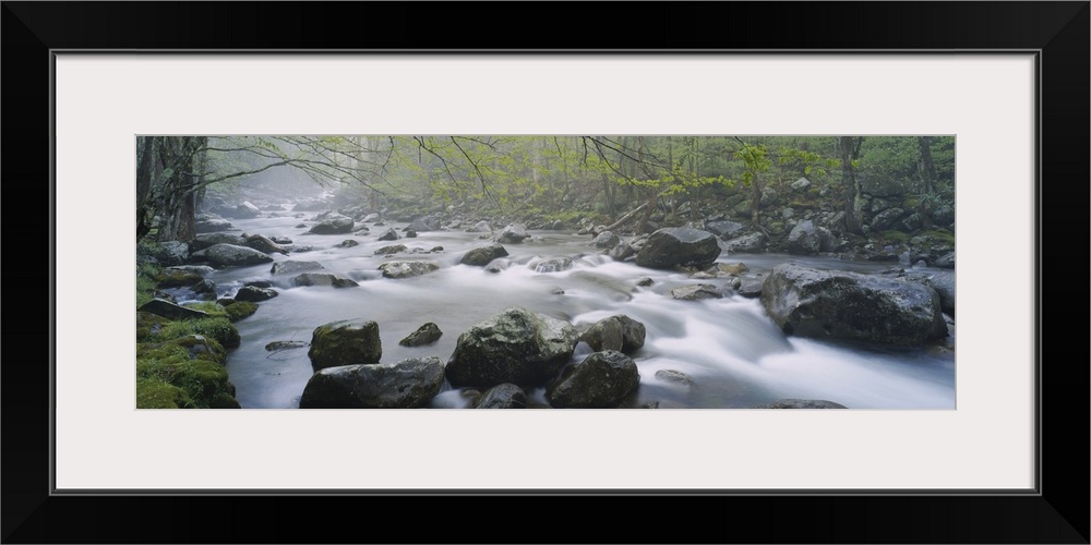 Wall art of water rushing over and through rocks in a river with a forest on either side.