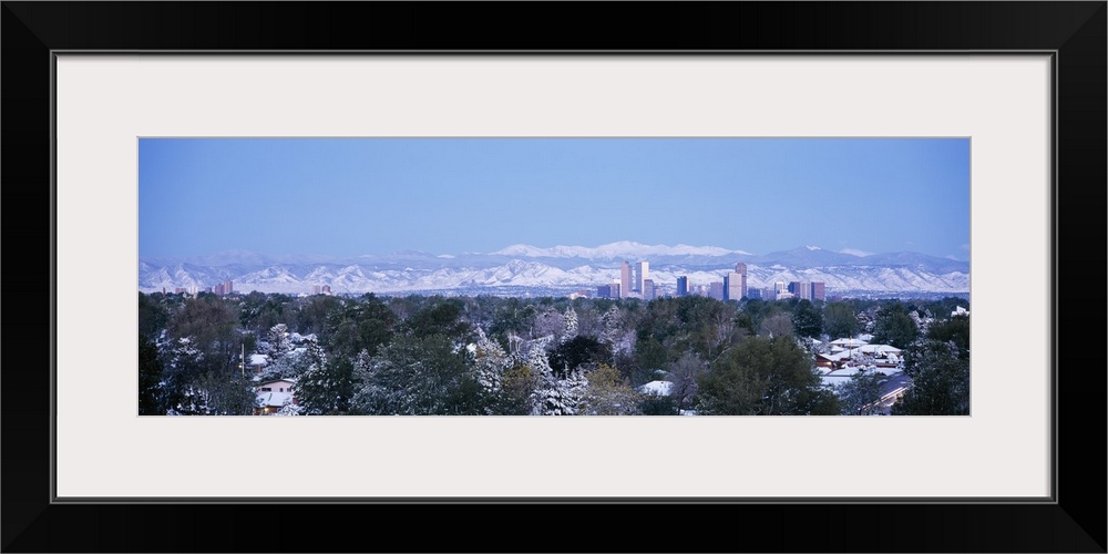 Panoramic photograph on a large wall hanging of a snow covered landscape surrounding houses in front of the city skyline a...