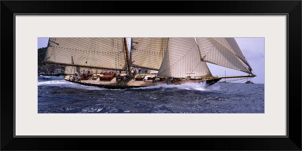 The body of a large sail boat is photographed in wide angle view as one side leans down into the water.