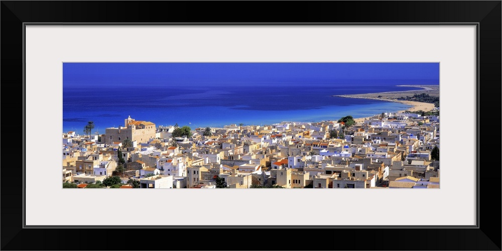 This is a landscape photograph of a coastal village and the sea beyond it in this panoramic wall art.