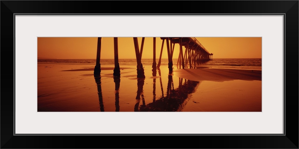 Big, panoramic photograph taken at an angle of Hermosa Beach Pier during a golden sunset, in Hermosa Beach, California.