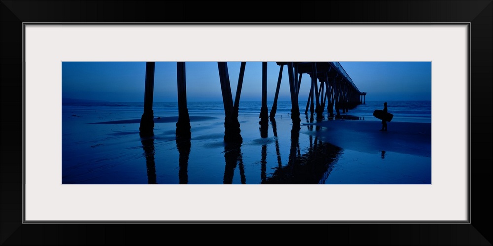 Big, landscape, panoramic photograph looking upward at an angle toward the Hermosa Beach Pier in California, at dusk. The ...