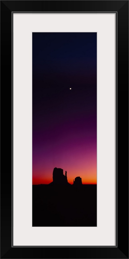 Vertical panorama of a crescent moon hanging in the sky high above the rock formation, The Mittens, as the last glow of su...