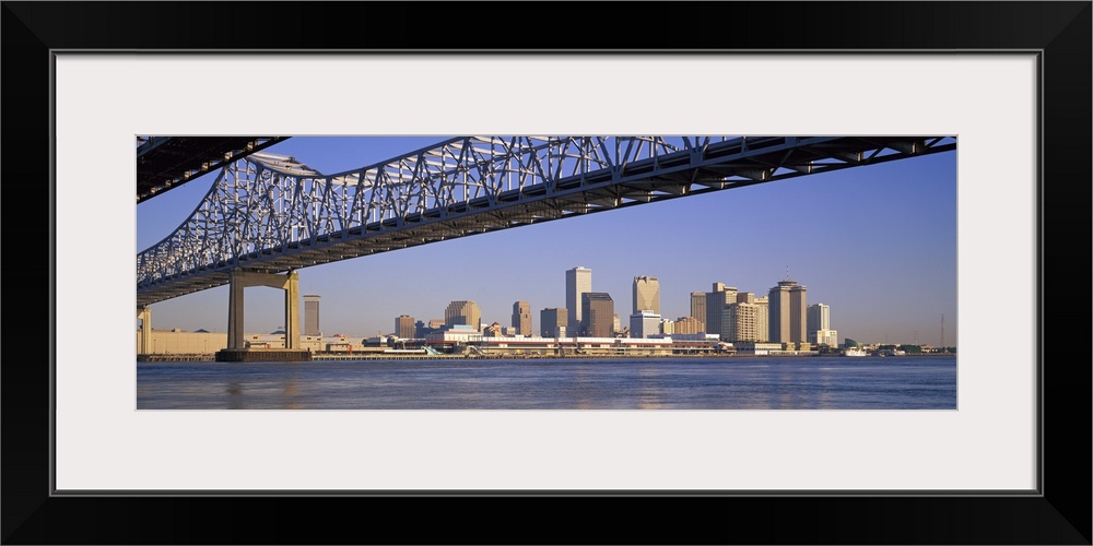 Part of the New Orleans skyline is photographed from a distance below the Crescent City Connection bridge.