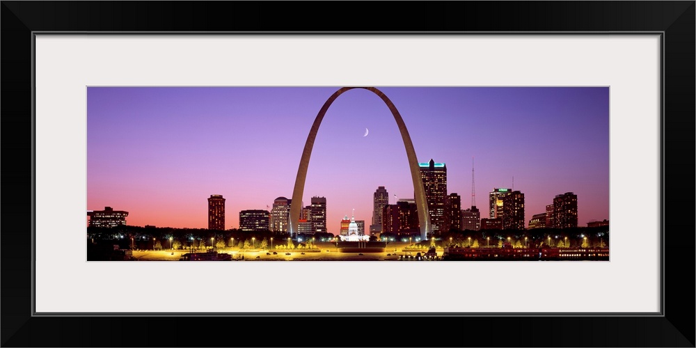 Panoramic photograph shows the skyline of St. Louis, Missouri reflecting into the Mississippi River within the foreground....