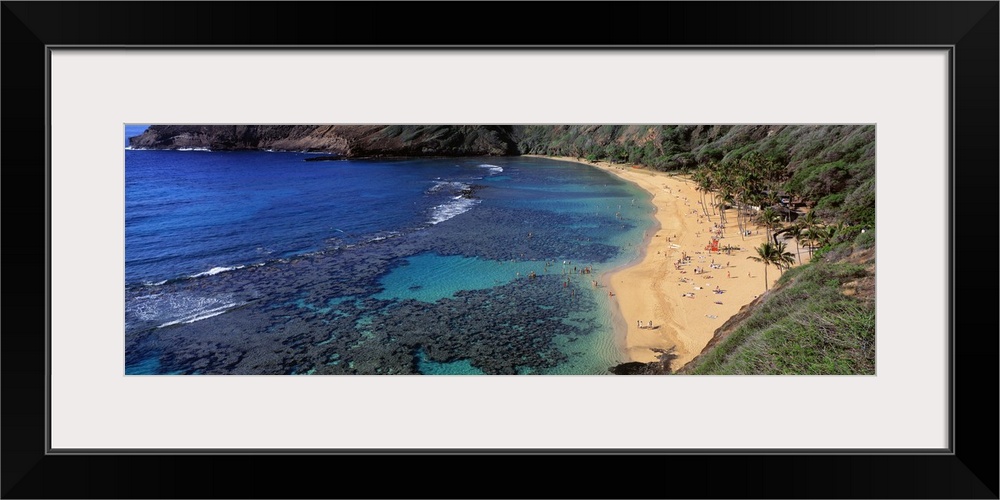 Panoramic photograph of inlet with coral and beach lined with mountains.