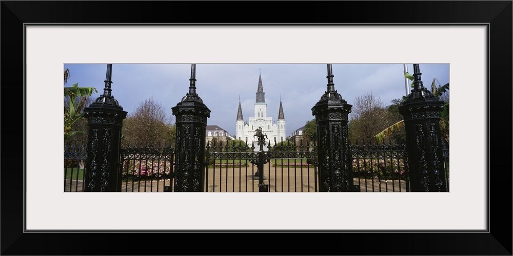 Panoramic photo on canvas of a big house of worship that is seen through iron fences located in Louisiana.