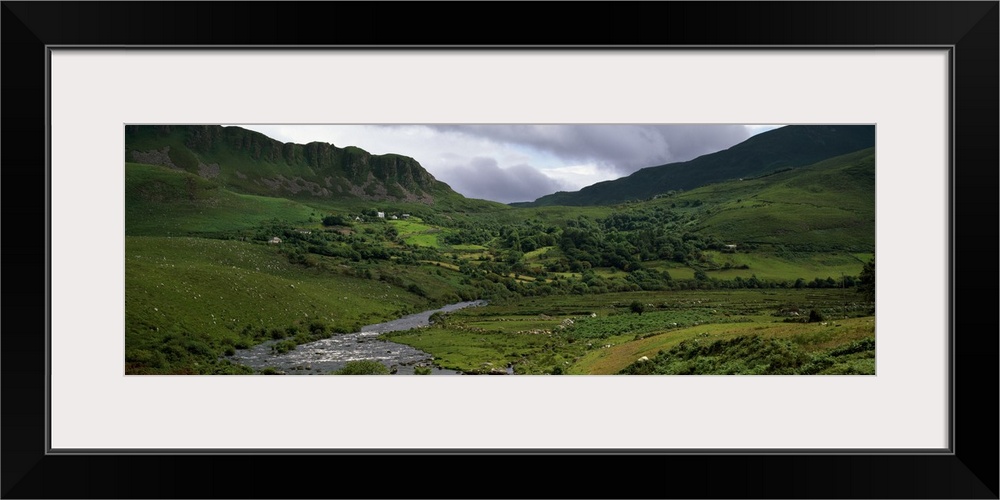 Stream through lush mountain landscape, distant cottages, Ireland