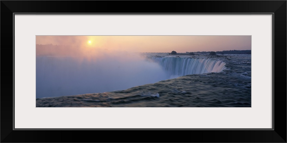 Big canvas print of water rushing down Niagara Falls with the sun rising in the distance.