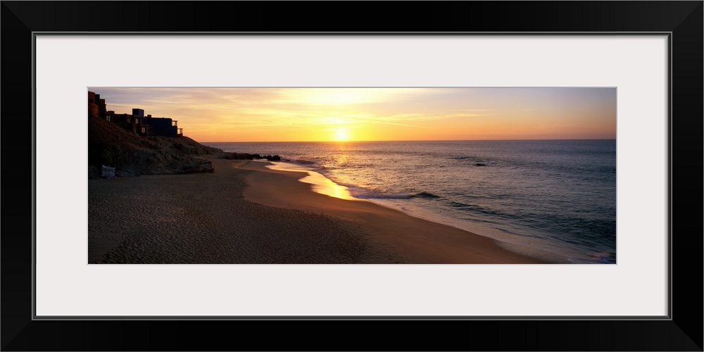 Panoramic photo of the sun rising over the beach in Los Cabos, Mexico.