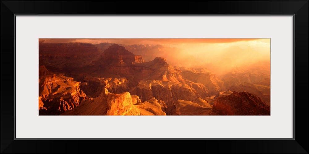 A panoramic photograph of the sunos rays shining on the rocky plateaus emerging from the canyon.