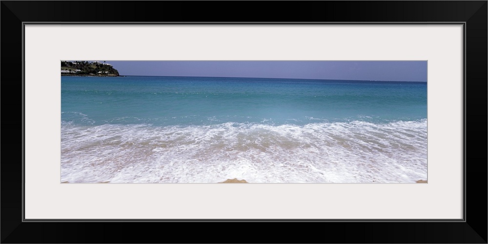 Panoramic image of waves washing ashore from a crystal clear ocean.