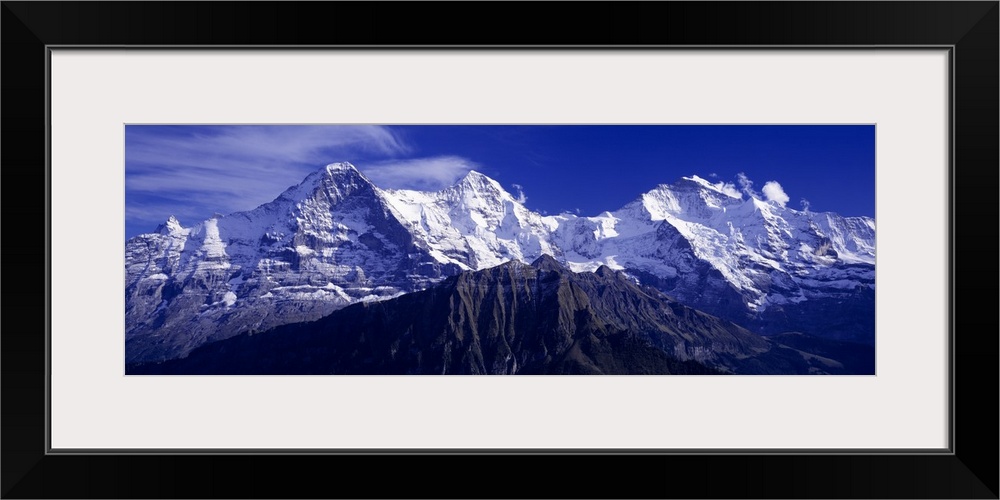 Giant, landscape photograph of snow covered Swiss mountains against a deep blue sky in Berner, Oberland, Switzerland.