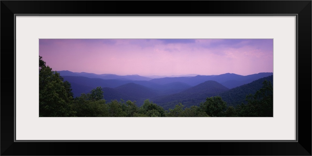 Wide angle photograph taken of the smoky mountains with some trees lining the bottom of the picture.