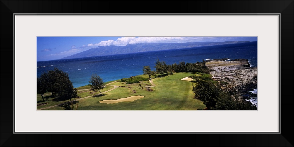 This panoramic photograph is a golf landscape overlooking the ocean from a tropical island.